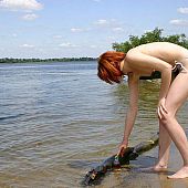 Cute redhead legal age teenager undresses on a public beach and goes swimming nude.